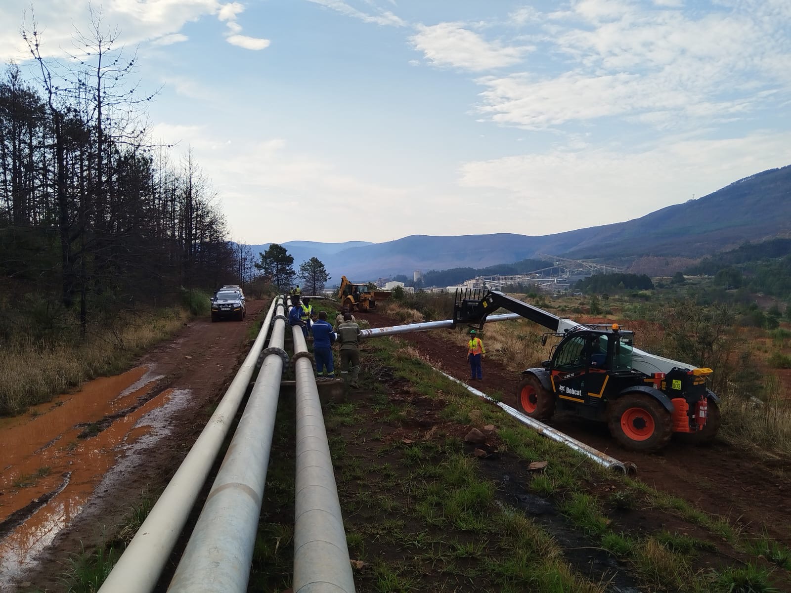 Wetpipe crew installing parallel overland slurry pipelines with a telehandler on a mining route